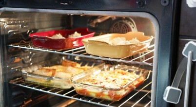 Inside of oven with multiple ceramic and glass trays of baked food