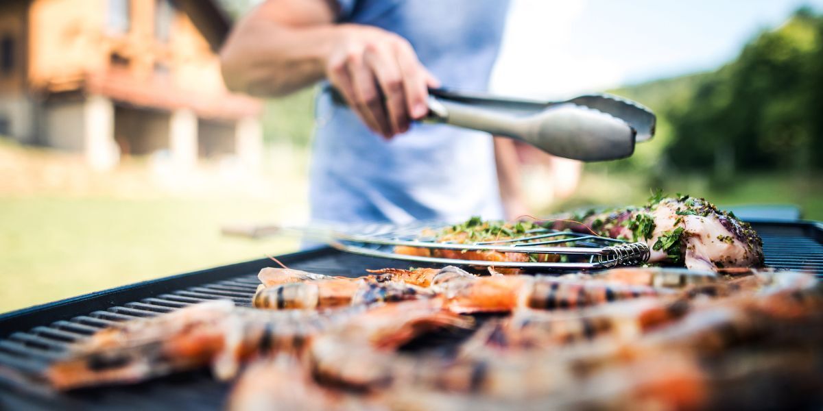 Close up of a man with tongs barbecuing