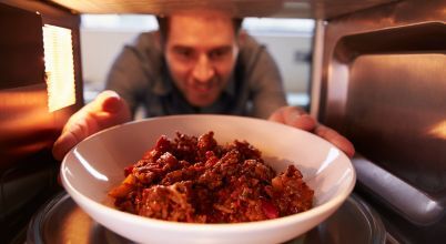 A man removes heated up leftovers from a microwave