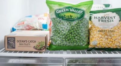 Commercial store bought frozen peas, corn and basa fish fillets in packaging in domestic home freezer
