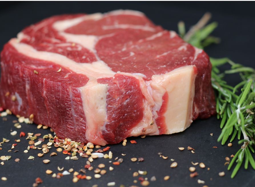 Raw steak with rosemary and pepper spices.