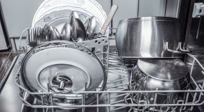 A dishwasher rack has clean saucepans, crockery and cutlery