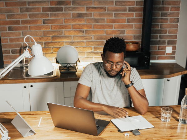 A man working from home is seated at the kitchen breakfast bar.